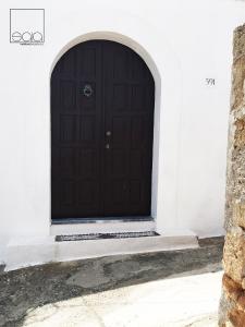 a black door in a white building with an archway at Sala Traditional Experience. Lindos in Lindos
