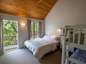 a bedroom with a bunk bed and a balcony at Kanuka House - Kaiteriteri Holiday Home in Kaiteriteri