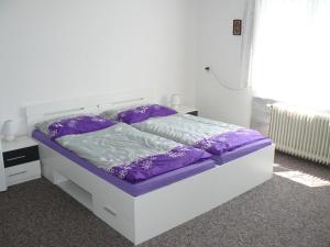 a white bed with purple sheets and pillows on it at Apartmán U paní Věrky in Sloup