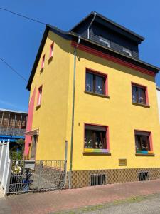 un edificio amarillo con ventanas rojas en una calle en T&T Ferienwohnung, en Rheinbrohl