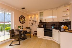 eine Küche mit weißen Schränken und einem Tisch vor einem Fenster in der Unterkunft Waldperle in Ostseebad Karlshagen