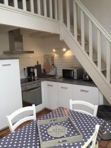 a kitchen with a table and a kitchen under a staircase at Gîte Ste Cécile plage in Camiers +3 photos