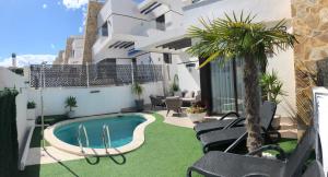 a patio with a swimming pool and chairs and a building at Villa Bianco in Orihuela Costa