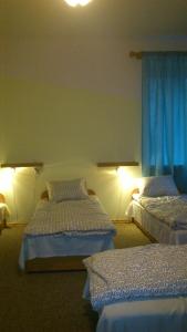 two beds in a room with blue curtains at Kwatery Pracownicze TOLEK in Warsaw