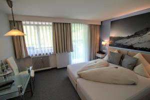 Habitación de hotel con cama blanca y escritorio en Hotel-Garni Fels en Riezlern