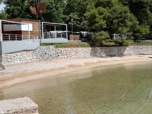 ein Haus mit einer Steinmauer neben einem Wasserkörper in der Unterkunft Villa „Drei Palmen“ in Sveti Filip i Jakov