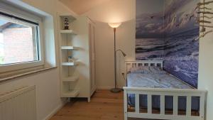 - une chambre avec un lit bébé et un grand tableau mural dans l'établissement Ferienhaus Möwe, à Butjadingen
