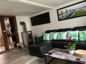 a living room with a black leather couch and a table at Ferienwohnung Kleiner Kalle in Melsungen