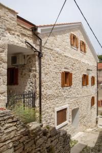 kamienny dom z drewnianymi oknami i kamienną ścianą w obiekcie Krka Waterfalls w mieście Skradin