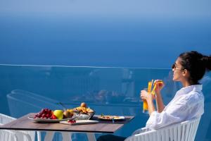 Una donna seduta a un tavolo con un cesto di frutta di Lilium Hotel Santorini a Firà