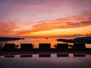 einen Pool mit Sonnenuntergang im Hintergrund in der Unterkunft Lilium Hotel Santorini in Fira