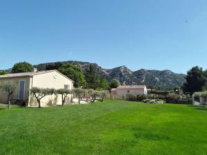 ein Haus mit grünem Rasen mit Bergen im Hintergrund in der Unterkunft Le Jardin des Tourterelles in Robion en Luberon