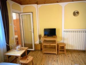 sala de estar con TV, mesa y sillas en Bobi Guest House, en Koprivshtitsa