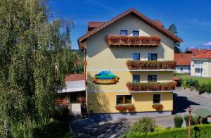 a yellow building with flower boxes on it at Hotel Alex in Sankt Kanzian