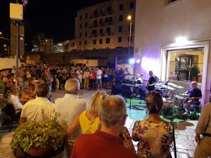 a crowd of people watching a band on a stage at La nassa fitta camere in Brindisi