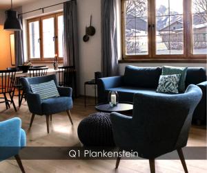 uma sala de estar com um sofá azul e cadeiras em Dachstein 7 em Gosau