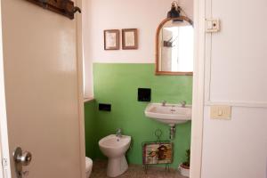 a green bathroom with a sink and a toilet at Ritornello B&B in Poviglio