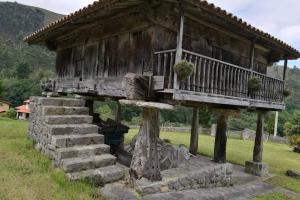 una vecchia casa con un portico su un tronco d'albero di Vivienda Vacacional La Perila a Rales