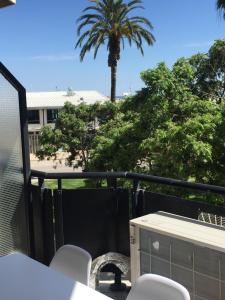 d'un balcon avec une table, des chaises et un palmier. dans l'établissement Apartamento delante del puerto deportivo ., à Sant Carles de la Ràpita