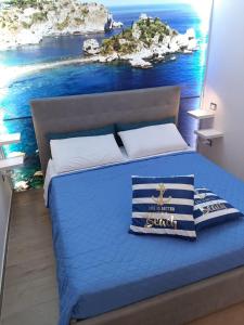 una camera con letto blu e dipinto dell'oceano di La casa nel vicolo a Giardini Naxos