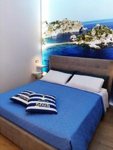 una camera con un letto blu e un dipinto sul muro di La casa nel vicolo a Giardini Naxos
