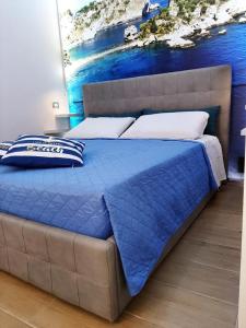 un letto con piumone blu e cuscini bianchi di La casa nel vicolo a Giardini Naxos