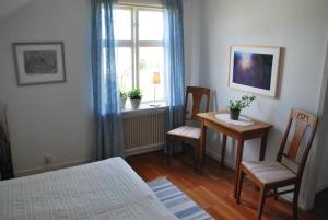a bedroom with a table and chairs and a window at Galleri Blå Porten in Alby