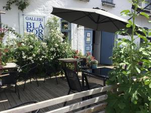 eine Terrasse mit einem Tisch, Stühlen und einem Sonnenschirm in der Unterkunft Galleri Blå Porten in Alby