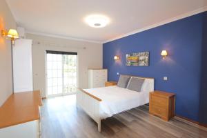 ein Schlafzimmer mit einer blauen Wand und einem weißen Bett in der Unterkunft Villa Nataliza 172- Clever Details in Vilamoura