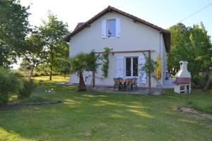 a small white house with a yard and a table and chairs at Maison spacieuse au calme in Morcenx