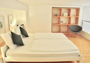 1 Schlafzimmer mit 2 weißen Betten und einem Stuhl in der Unterkunft Modern Family Apartment in Interlaken Center in Interlaken