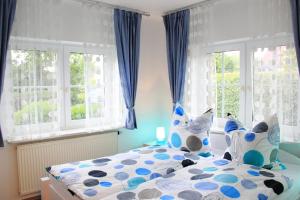 Schlafzimmer mit einem Bett mit blauen Vorhängen und Fenstern in der Unterkunft Jever-Ferienhaus Gartenblick in Jever