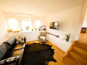 sala de estar con sofá de cuero negro y sala de estar con ventana en Lutterbach, en Monschau