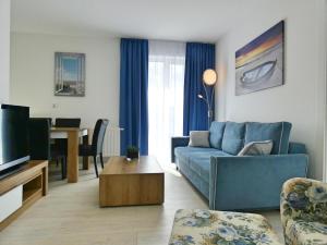 ein Wohnzimmer mit einem blauen Sofa und einem Tisch in der Unterkunft AZURE Baltic Apartamenty B&M in Kołobrzeg