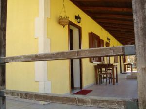 Casa amarilla con porche con mesa y sillas en Agriturismo Centuria en San Pio delle Camere