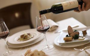 a person pouring wine into a wine glass on a table at Park Hotel Villa Carpenada in Belluno