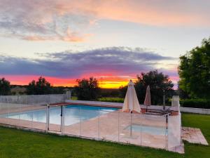 a pool with two umbrellas and a sunset at Monte da Boavista - Country family house in Alter do Chão