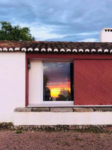 a red and white house with a window with a sunset at Monte da Boavista - Country family house in Alter do Chão