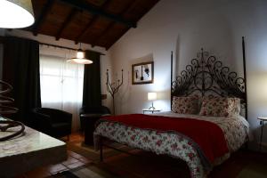 una camera da letto con un grande letto con una coperta rossa di Quinta dos Trevos - Artes e Ofícios a Ladoeiro