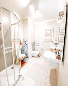 a white bathroom with a shower and a sink at Rezydencja Maritimo Kołobrzeg Port in Kołobrzeg