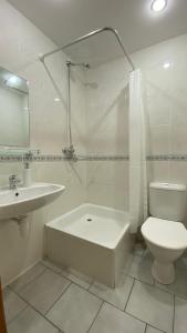 baño blanco con bañera, aseo y lavamanos en Dana Guest House, en Roja