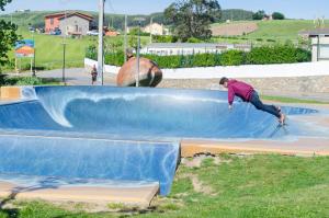 Un hombre montando una patineta en una rampa en un parque de patinaje. en Camping Playa de Ajo, en Ajo
