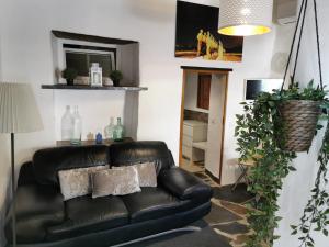 a living room with a black leather couch at Sossego da Carminho in Monsaraz