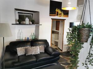 Una sala de estar con un sofá de cuero negro. en Sossego da Carminho, en Monsaraz
