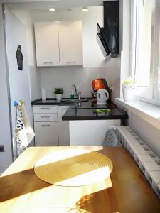 a kitchen with white cabinets and a wooden table at Apartament Parkowy Rabka in Rabka-Zdrój