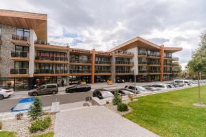 a large building with cars parked in a parking lot at Apartment Marco Hrebienok in Starý Smokovec