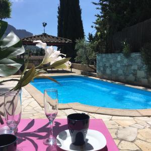 een tafel met glazen en een vaas met bloemen naast een zwembad bij BOUTIQUE HOSTEL BY Cassis in Cassis