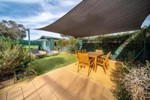 HawkerFlinders Ranges Bed and Breakfast的露台配有桌椅和遮阳伞