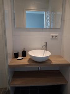 W łazience znajduje się biała umywalka i lustro. w obiekcie Vakantiewoning 100m van het strand met 1 Slaapkamer w mieście Westkapelle