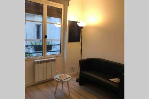 ein Wohnzimmer mit einem schwarzen Sofa und einem Fenster in der Unterkunft Appartement de charme à Montmartre in Paris
